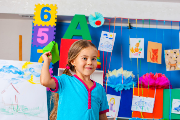 Dziewczyna dzieci gospodarstwa origami samolotu w przedszkolu . - Zdjęcie, obraz