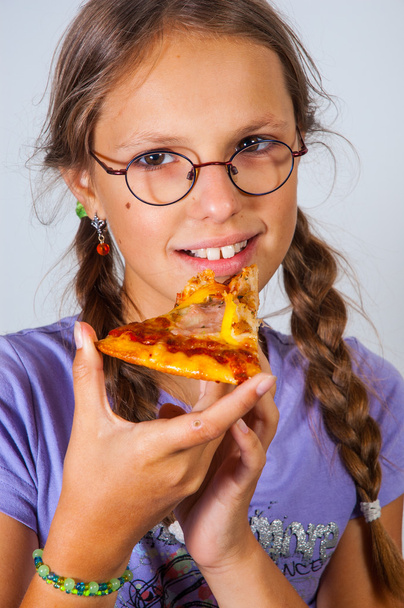  young brunette girl eating a piece of pizza against a white background. - Foto, immagini