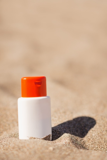 Bottle of sun block creme on sand - Fotoğraf, Görsel
