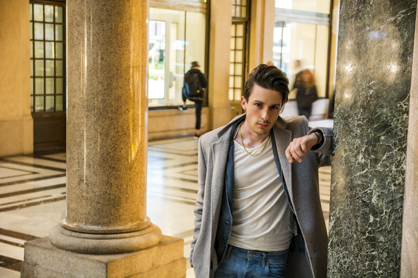 Portrait of handsome young man leaning on marble column - 写真・画像