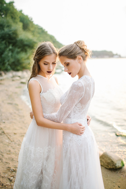 Twin sisters in wedding dress on the seashore - Foto, afbeelding