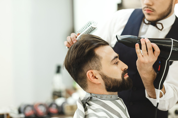 Темноволосий перукар робить зачіску
 - Фото, зображення