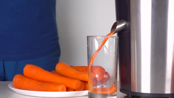 Man in blue clothes making carrot juice with polished juicer. 4K shot - Séquence, vidéo