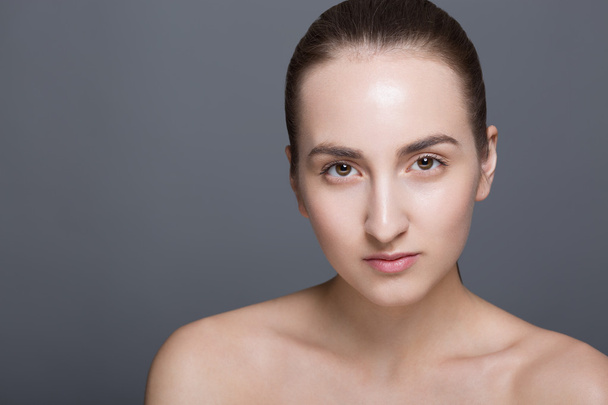 Beauty fashion vogue style face of caucasian brunette with elegant make-up, blue eyes, natural lips touching perfect skin. Close-up studio portrait isolated. Black background with grey spot. - 写真・画像