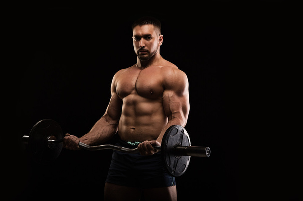 handsome muscular bodybuilder posing on a black background - Фото, зображення