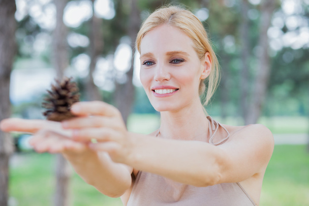 Young beautiful happy woman in park holds pinecone, summer outdoors - Foto, Bild