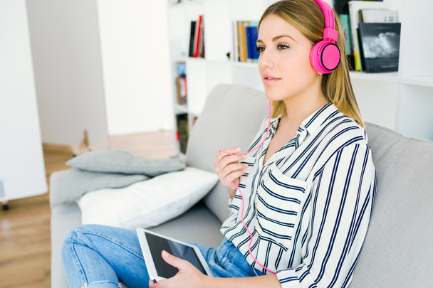 Όμορφη νεαρή γυναίκα να ακούτε μουσική με ψηφιακή δισκίο. - Φωτογραφία, εικόνα
