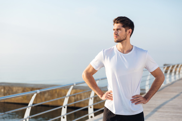 Male athlete standing on pier near the sea - Photo, image