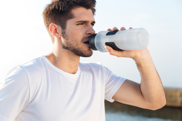 Sportsman in white shirt drinking water outdoors - Zdjęcie, obraz