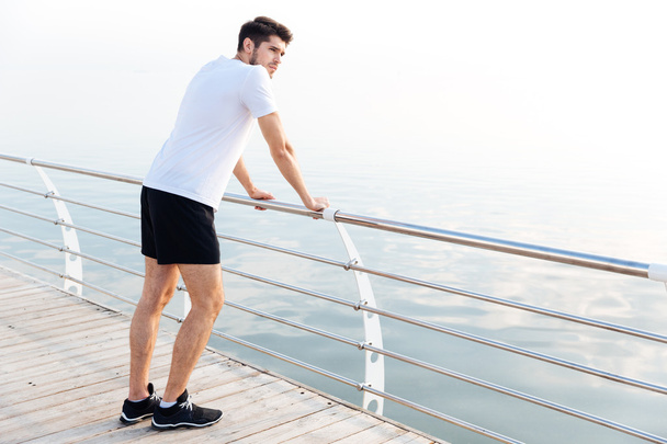 Man athlete resting after running standing on pier - Photo, Image