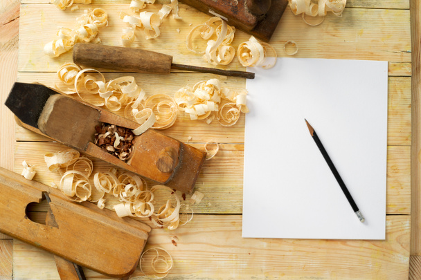 Bílý list na dřevěný stůl pro tesařské nástroje s pilinami. - Fotografie, Obrázek