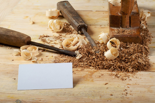 Επαγγελματική κάρτα στο ξύλινο τραπέζι για τα εργαλεία ξυλουργών με πριονίδι. - Φωτογραφία, εικόνα
