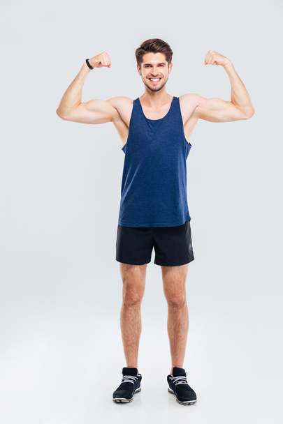 Full length portrait of a smiling man showing his biceps - Photo, Image