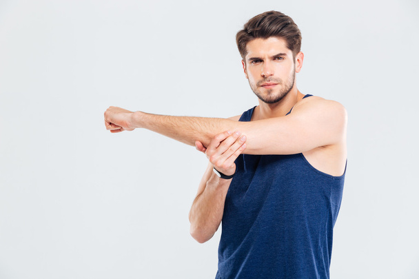 Handsome young sportsman stretching hands during workout - Foto, imagen