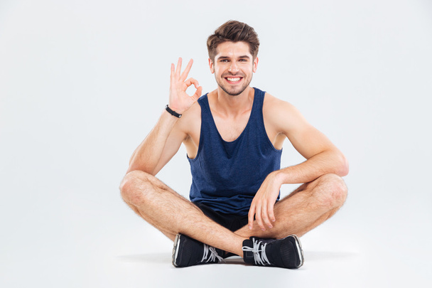 Smiling young man athlete sitting and showing ok sign - Foto, Imagem