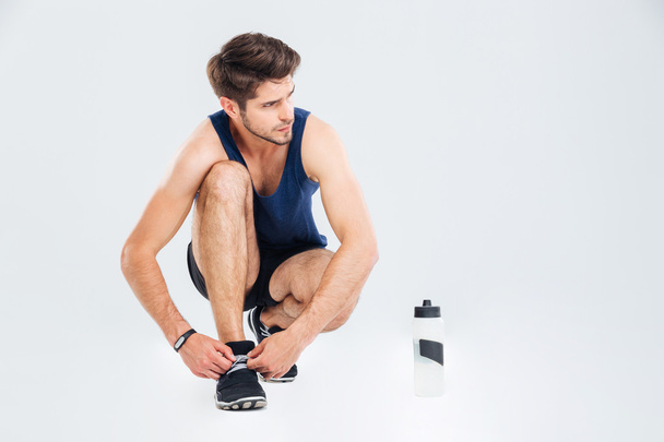 Man athlete with bottle of water tie shoelaces on sneakers - Foto, Imagem