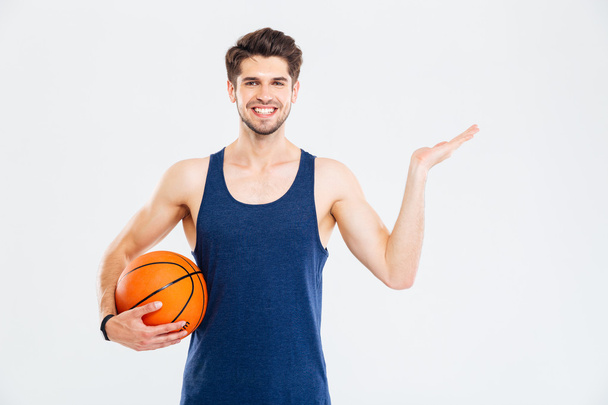 Cheerul young sportsman with basketball ball holding copyspace on palm - Foto, Bild