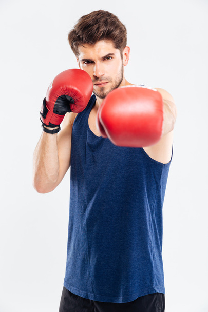 Portrait of a man hitting at camera in boxing gloves - Photo, Image