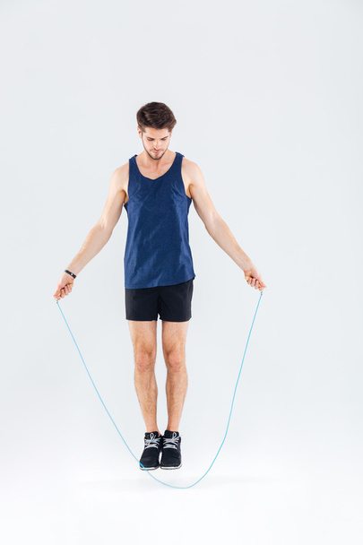 Full length portrait of a man jumping with skipping rope - Foto, afbeelding