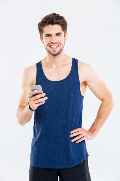 Happy young sportsman standing and using smartphone - Φωτογραφία, εικόνα