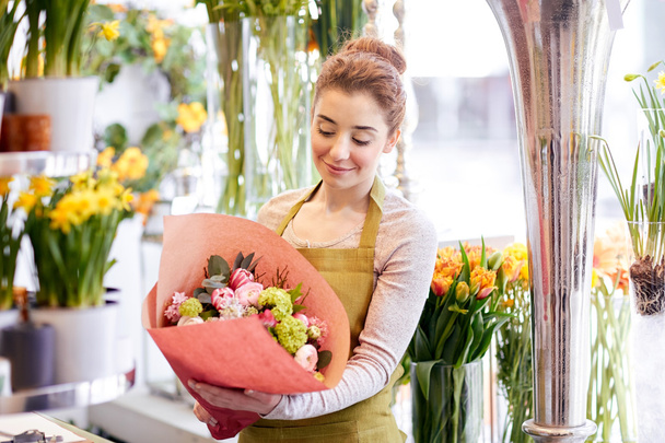 smiling florist woman with bunch at flower shop - Foto, Bild