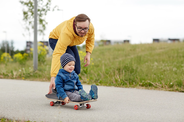 happy father and little son riding on skateboard - Foto, Bild