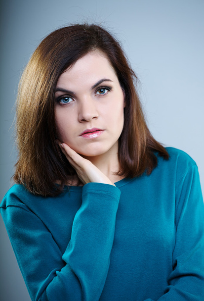 вдумчивая девушка в голубой футболке смотрит вверх на сером фоне
 - Фото, изображение