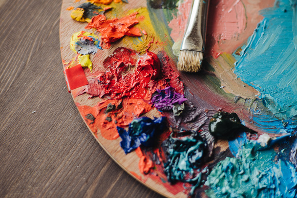 mixes oil paints on palette with brush - 写真・画像