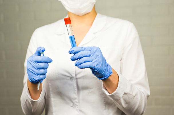 science, chemistry, biology, medicine, people concept - young female scientist holding tube with sample making and test or research in clinical laboratory - Foto, Imagem