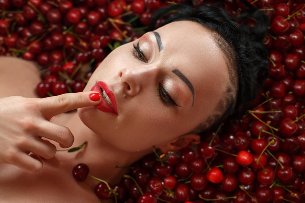 Girl bodybuilder on the background of ripe red cherries - Valokuva, kuva