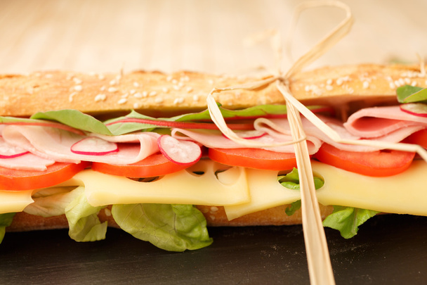 kanapkę w francuski bagietki, ser, szynka, pomidor, rzodkiewka, sałata zbliżenie. domowe jedzenie. pieczywo chrupkie - Zdjęcie, obraz