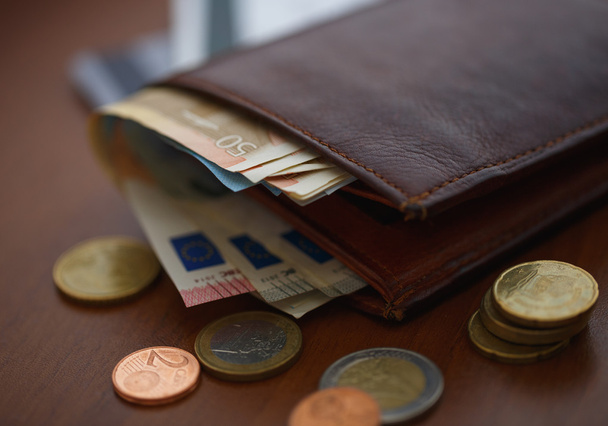 Bruin portemonnee met euro geld binnen en munten, creditcards in de buurt van - Foto, afbeelding