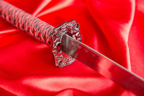 Japanese sword takana on red satin background - Foto, Imagem