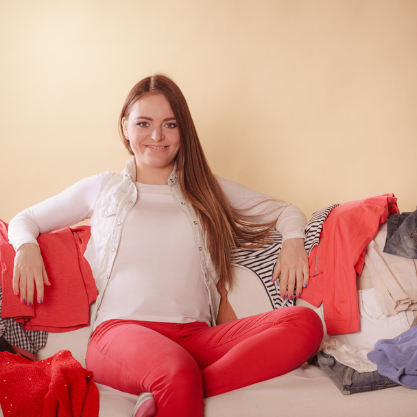 Happy woman sitting on sofa in messy room at home. - Photo, image