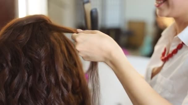 mladá žena a kadeřnictví s vlasy železa, takže účes v kadeřnictví - Záběry, video