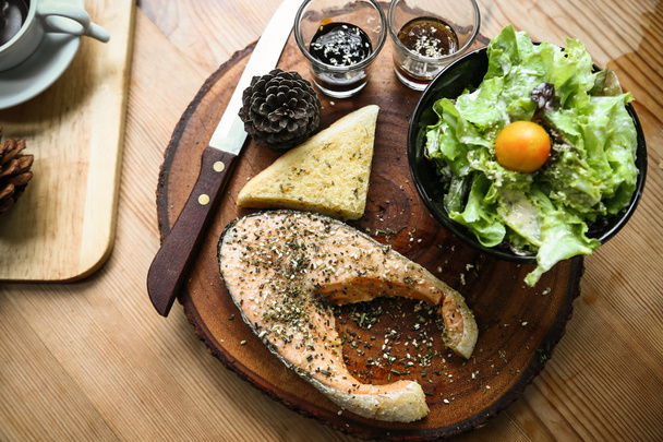 Φιλέτο σολομού στο ξύλινο τραπέζι σε εστιατόριο, φρέσκια μπριζόλα για υγιεινό φαγητό και καθαρά τρόφιμα ή φρέσκα τρόφιμα για τη διατροφή, διεθνή μπριζόλα στο πιάτο με φρέσκα λαχανικά ή σαλάτα στο εστιατόριο. - Φωτογραφία, εικόνα