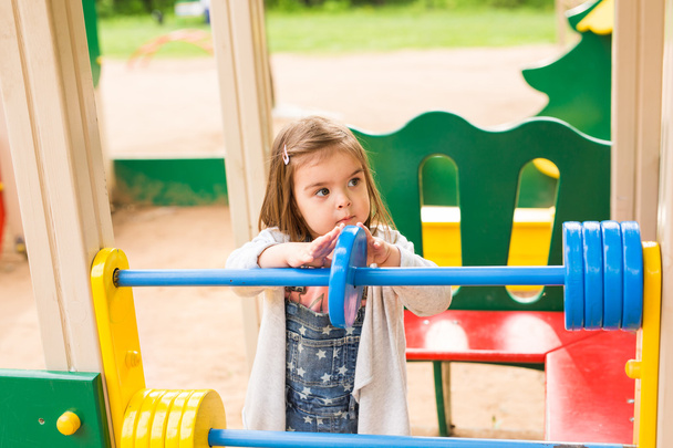 Little girl on a playground. Child playing outdoors in summer. - Photo, Image
