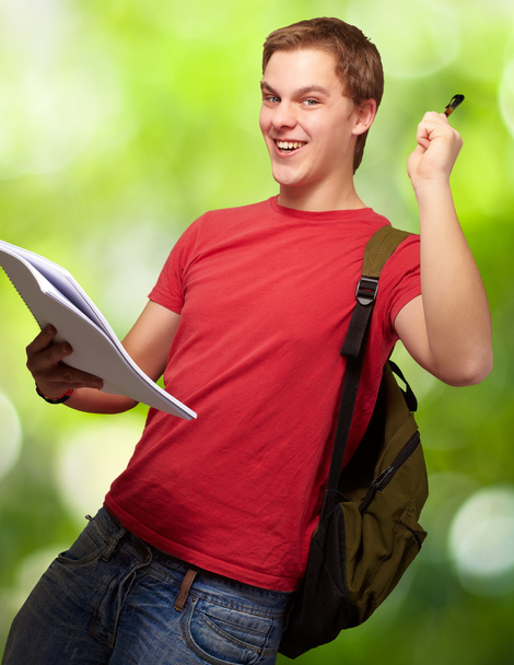Retrato de estudante bonito segurando notebook e caneta contra um
 - Foto, Imagem