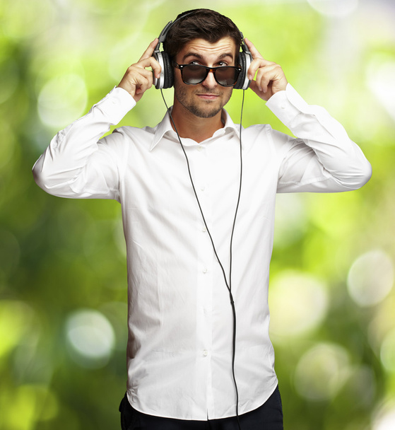 Портрет молодого человека, слушающего музыку с помощью наушников
 - Фото, изображение