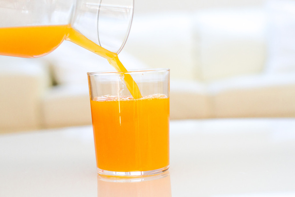 Verre de jus d'orange sur une table dans un salon
 - Photo, image