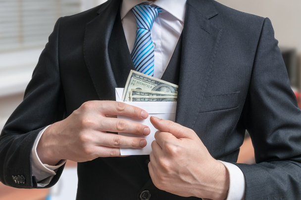 Corruption concept. Businessman is hiding letter full of money or bribe in suit jacket. - Fotó, kép