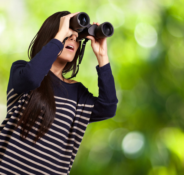 Portrait of young girl looking through a binoculars against a na - Photo, Image