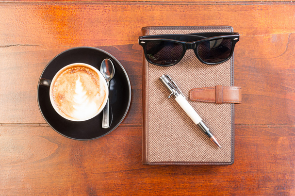 Up view of notebook pen sun glasses and coffee - Photo, Image