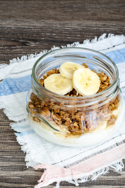 Granola, yoghurt and a banana in jar on rustic cloth - Zdjęcie, obraz