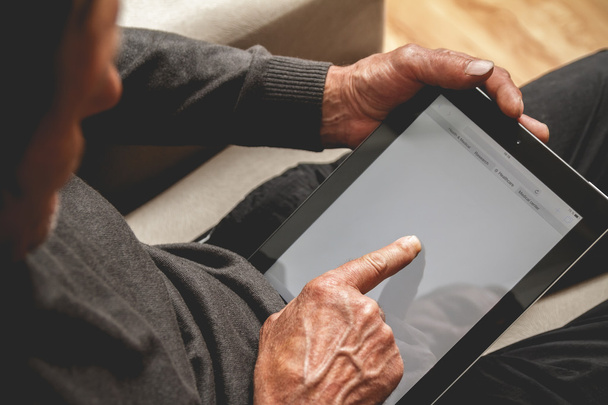 Senior holding a tablet in hands - Foto, afbeelding