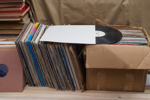 Bild im Retro-Stil einer Sammlung alter Schallplatten mit Hüllen auf Holzgrund. Blättern in der Schallplattensammlung. Musikalischer Hintergrund. Kopierraum - Foto, Bild