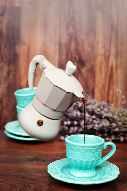 Levitation coffee. Percolator coffee with the lid closed. Pastel blue coffee maker pouring coffee into a cup. Dry lavender behind. Dark wood background - Fotografie, Obrázek