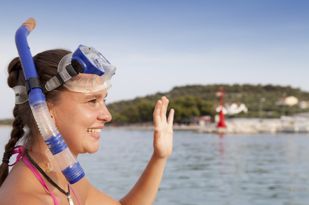 Lovely girl at the seaside wearing a diving mask and waving hello - Photo, Image