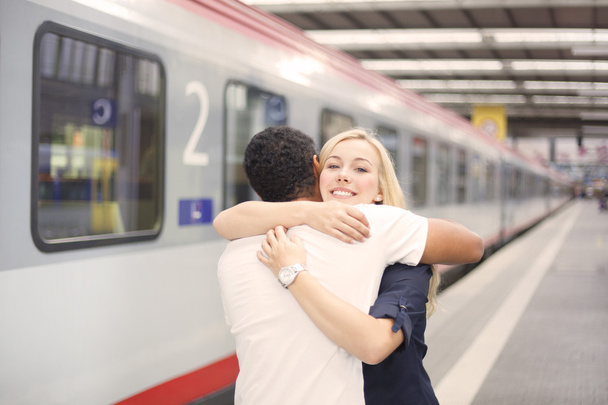 Interracial couple hugging at the train station - Foto, afbeelding