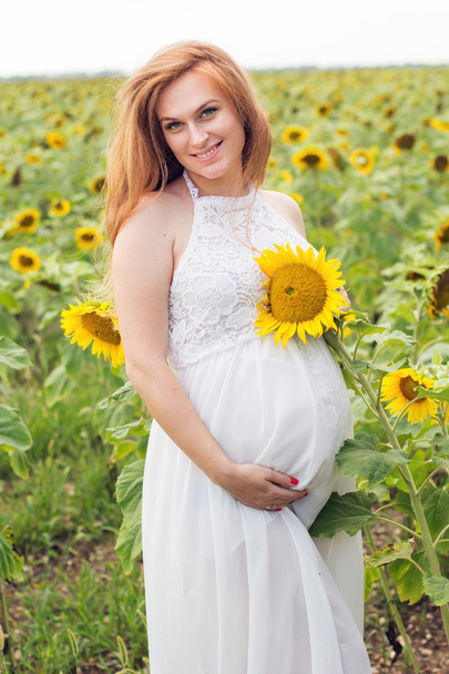Pregnant woman in the field with sunflowers - Valokuva, kuva